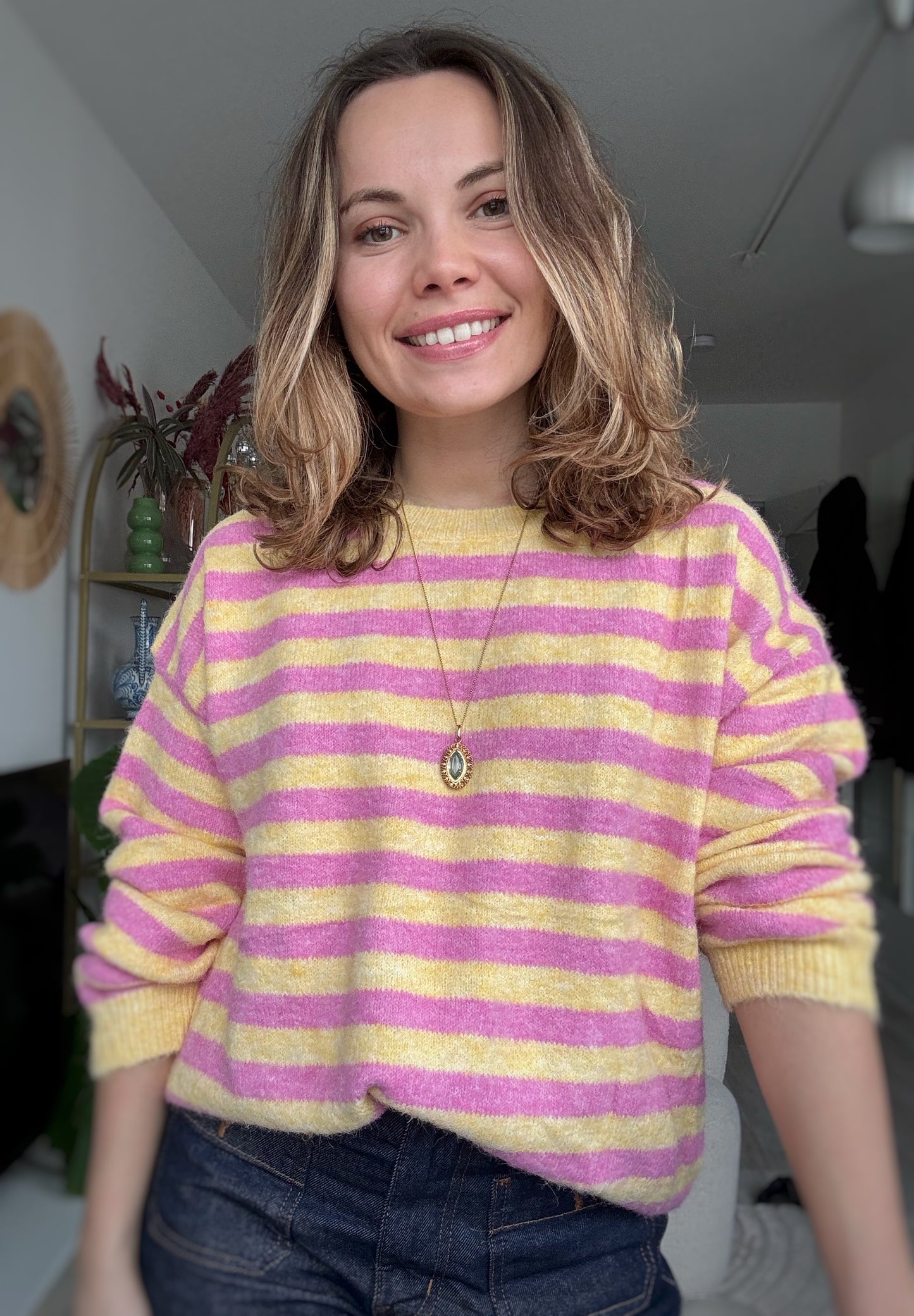 Femme portant un pull rayé rose et jaune en maille douce avec un jean, style chic et décontracté