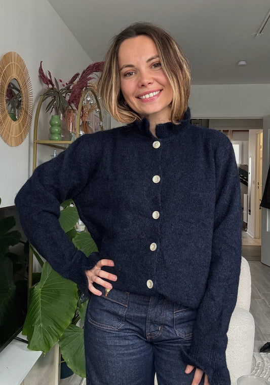 Femme portant le gilet Élise bleu marine en maille douce avec boutons nacrés, style chic et intemporel