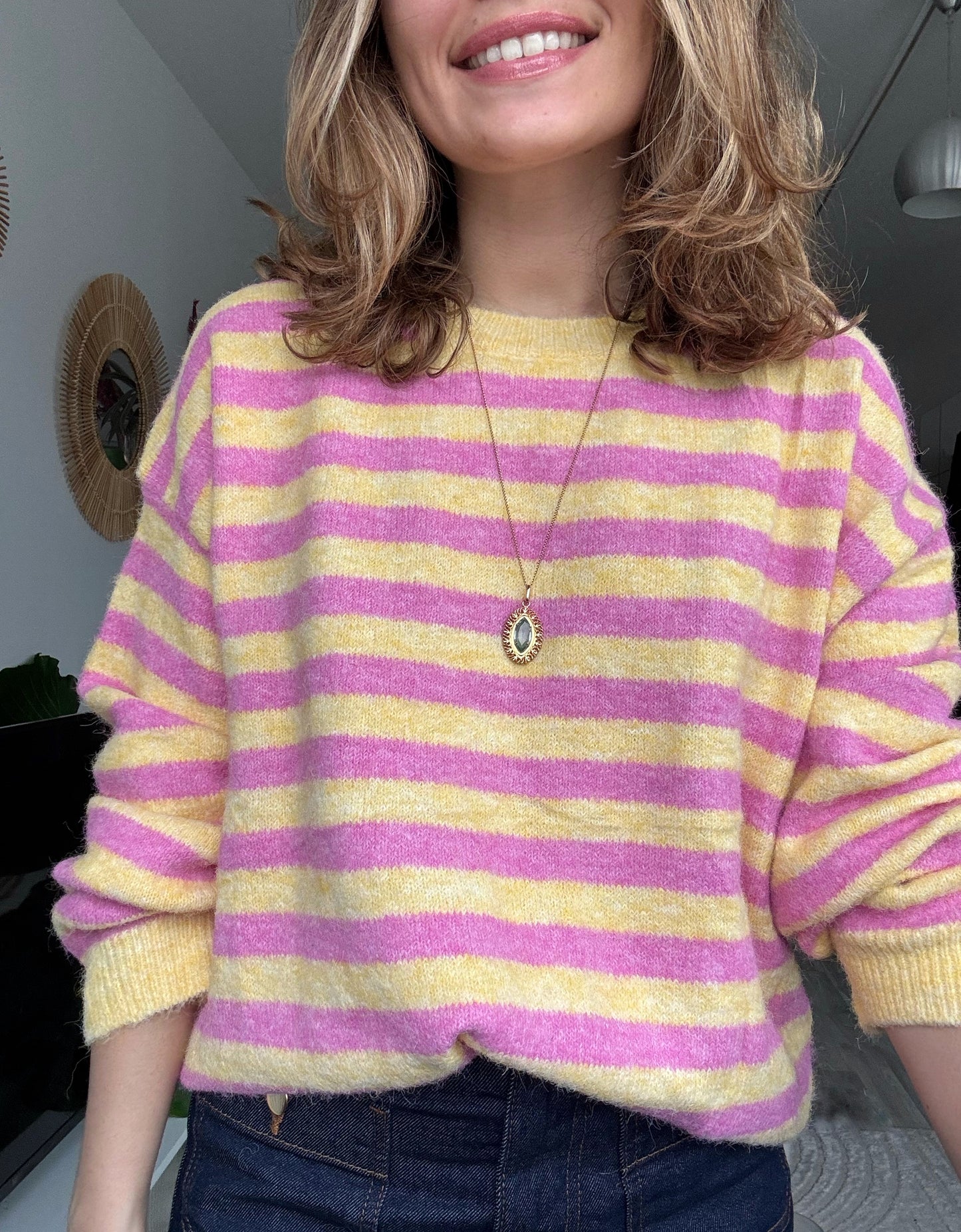 Femme portant un pull rayé rose et jaune en maille douce avec un jean, style chic et décontracté