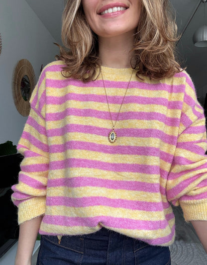 Femme portant un pull rayé rose et jaune en maille douce avec un jean, style chic et décontracté