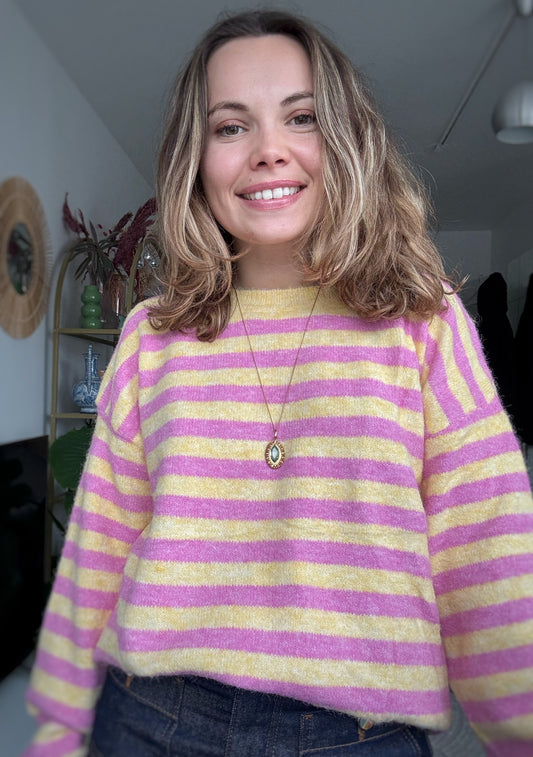 Femme portant un pull rayé rose et jaune en maille douce avec un jean, style chic et décontracté